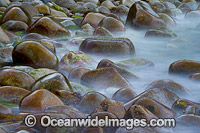 Wave breaking over smooth rocks, situated in Bluestone Bay, Freycinet National Park, Tasmania, Australia.